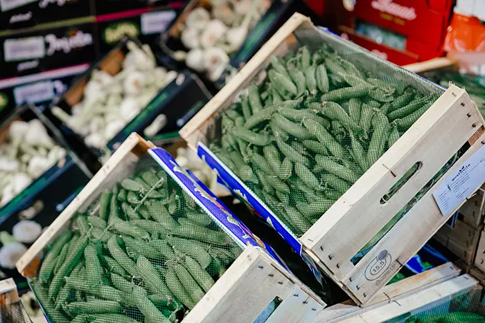 grüne Bohnen in Holz-Steigen, verschlossen mit einem blauen Drahtnetz