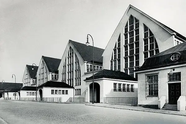 historische Schwarz-Weiß-Aufnahme der Großmarkthalle München. 4 spitze Giebel von hohen Hallen mit vielen kleinen Fenstern. Davon kleine Eingangsgebäude