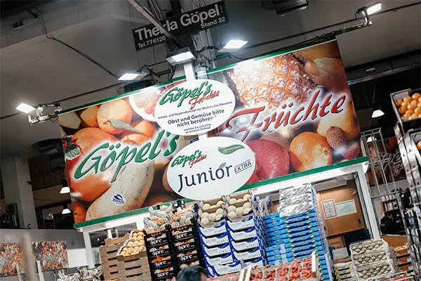Verlaufsstand Göpels Früchte mit großem angestrahlten Schild darüber und verschiedenen Steigen von Obst und Gemüse